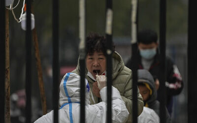 A woman has her routine COVID-19 test at a coronavirus testing site setup inside a residential compound in Beijing, Thursday, Nov. 24, 2022. (AP/Andy Wong)