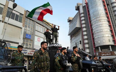 An anti-riot police officer waves a representation of the Iranian flag during a street celebration after Iran's national soccer team defeated Wales in Qatar's World Cup, at Sadeghieh Square in Tehran, Iran, November 25, 2022. (AP Photo/Vahid Salemi)