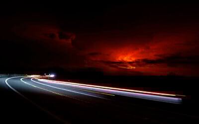 In this long camera exposure, cars drive down Saddle Road as Mauna Loa erupts in the distance, Monday, Nov. 28, 2022, near Hilo, Hawaii. Mauna Loa, the world's largest active volcano erupted Monday for the first time in 38 years. (AP Photo/Marco Garcia)