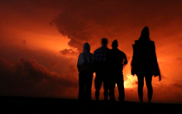 People watch the glow from lava erupting from Hawaii's Mauna Loa volcano, Monday, Nov. 28, 2022 in Hilo, Hawaii. (AP Photo/Caleb Jones)