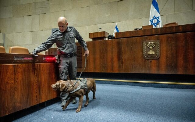 A K9 officer inspects the Knesset plenum ahead of the swearing-in of the new parliament, November 14, 2022. (Yonatan Sindel/Flash90) A K9 officer inspects the Knesset plenum ahead of the swearing-in of the new parliament, November 14, 2022. (Yonatan Sindel/Flash90)