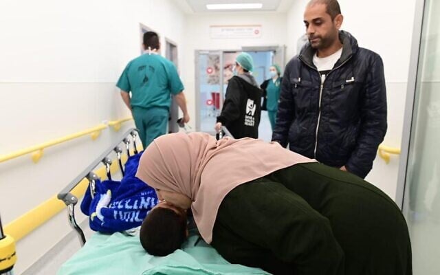 The grandmother of 5-year-old Gazan Amir Yichya Mabchuch kisses him on the head before he is taken in for open-heart surgery, at the Wolfson Medical Center in Holon, on November 21, 2022. (Tomer Noyberg/Save a Child's Heart)