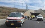 Am ambulance is seen at the site of a collision between a motorcyclist and a private vehicle on Road 531 near Herzliya on November 27, 2022. (Magen David Adom)