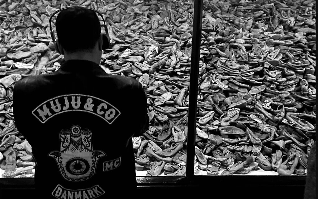 A member of the MuJu & Co. motorcycle club looks at shoes of victims of Auschwitz, during their visit to the concentration camp memorial on October 1, 2022. (Courtesy Dan Meyrowitsch)