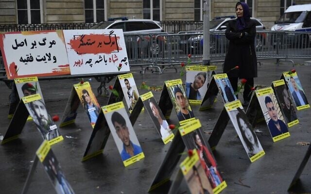 A protester stands next to placards with portraits of the victims of Iran's repression, near the French National Assembly in Paris on December 6, 2022. (Julien De Rosa/AFP) A protester stands next to placards with portraits of the victims of Iran's repression, near the French National Assembly in Paris on December 6, 2022. (Julien De Rosa/AFP)