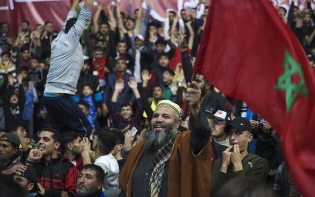 Palestinan soccer fans lift Moroccan flags and cheer as they watch the Qatar 2022 World Cup round 16 soccer match between Portugal and Morocco in Gaza City, on December 10, 2022. (MOHAMMED ABED / AFP)