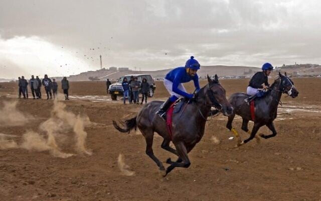 Jockeys compete in a weekly horse-racing competition at a field near the Bedouin village of Abu Tlal in southern Israel near Beersheva on November 25, 2022. (Menahem Kahana/AFP) Jockeys compete in a weekly horse-racing competition at a field near the Bedouin village of Abu Tlal in southern Israel near Beersheva on November 25, 2022. (Menahem Kahana/AFP)