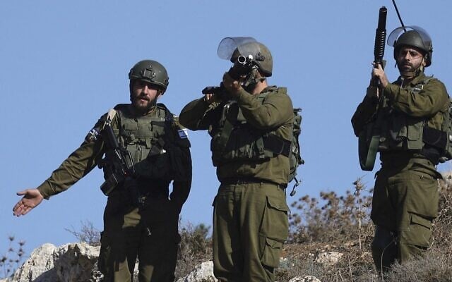 Israeli soldiers stand watch during clashes with Palestinian demonstrators in Beit Dajan, near Nablus, on December 16, 2022. (Jaafar Ashtiyeh/AFP) Israeli soldiers stand watch during clashes with Palestinian demonstrators in Beit Dajan, near Nablus, on December 16, 2022. (Jaafar Ashtiyeh/AFP)