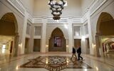 Men walk near a framed picture depicting Jordan's reigning King Abdullah II as they cross the main hall at the King Hussein Bin Talal Convention Centre near the town of Sweimeh in central-west Jordan on December 18, 2022 two days ahead of the "Baghdad Conference for Cooperation and Partnership." (Khalil MAZRAAWI / AFP)