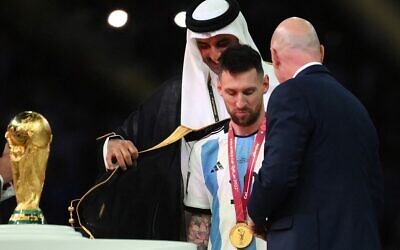 Qatar's Emir Sheikh Tamim bin Hamad al-Thani, left, helps Argentina's forward Lionel Messi put on an bisht, a traditional Arab robe, as FIFA President Gianni Infantino, right, watches after the Qatar 2022 World Cup final soccer match between Argentina and France at Lusail Stadium in Lusail, north of Doha on December 18, 2022. (FRANCK FIFE / AFP)
