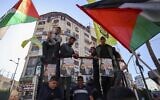 Palestinians wave their national flags and hold photos of Nasser Abu Hmeid during a demonstration following his death in an Israeli prison in the West Bank city of Ramallah on December 20, 2022. (Abbas Momani/AFP)