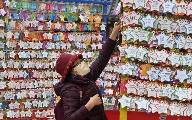 A Buddhist follower attaches name cards with wishes during celebrations for the New Year at Jogye temple in central Seoul on December 31, 2022. (Jung Yeon-je / AFP) A Buddhist follower attaches name cards with wishes during celebrations for the New Year at Jogye temple in central Seoul on December 31, 2022. (Jung Yeon-je / AFP)