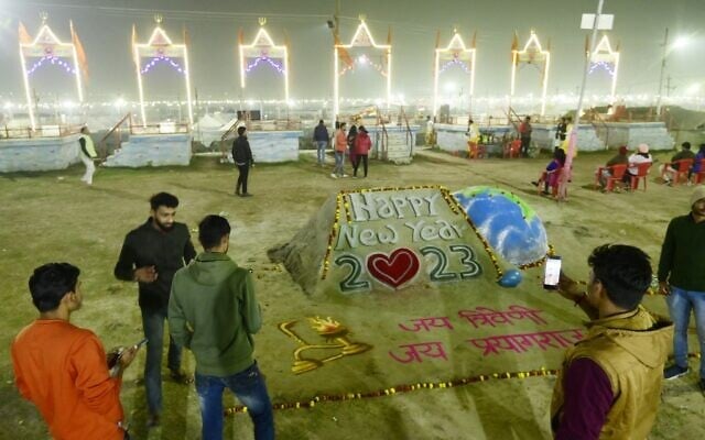 People take pictures near a sand sculpture for New Year at the Sangam area, the confluence of the rivers Ganges, Yamuna and mythical Saraswati, in Prayagraj, India, on December 31, 2022. (Sanjay Kanojia/AFP) People take pictures near a sand sculpture for New Year at the Sangam area, the confluence of the rivers Ganges, Yamuna and mythical Saraswati, in Prayagraj, India, on December 31, 2022. (Sanjay Kanojia/AFP)