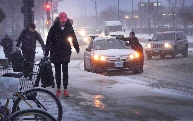 Pedestrians navigate a snow-covered sidewalk as temperatures hang in the single-digits on December 22, 2022 in Chicago, Illinois (Scott Olson/Getty Images/AFP) Pedestrians navigate a snow-covered sidewalk as temperatures hang in the single-digits on December 22, 2022 in Chicago, Illinois (Scott Olson/Getty Images/AFP)