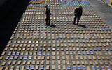 In this Thursday, Aug. 10, 2017 file photo, police officers walk among packages of seized cocaine at the Pacific port of Buenaventura, Colombia, after about one ton of cocaine was seized in a container during an operation by counternarcotics police at the port. (AP/Fernando Vergara)