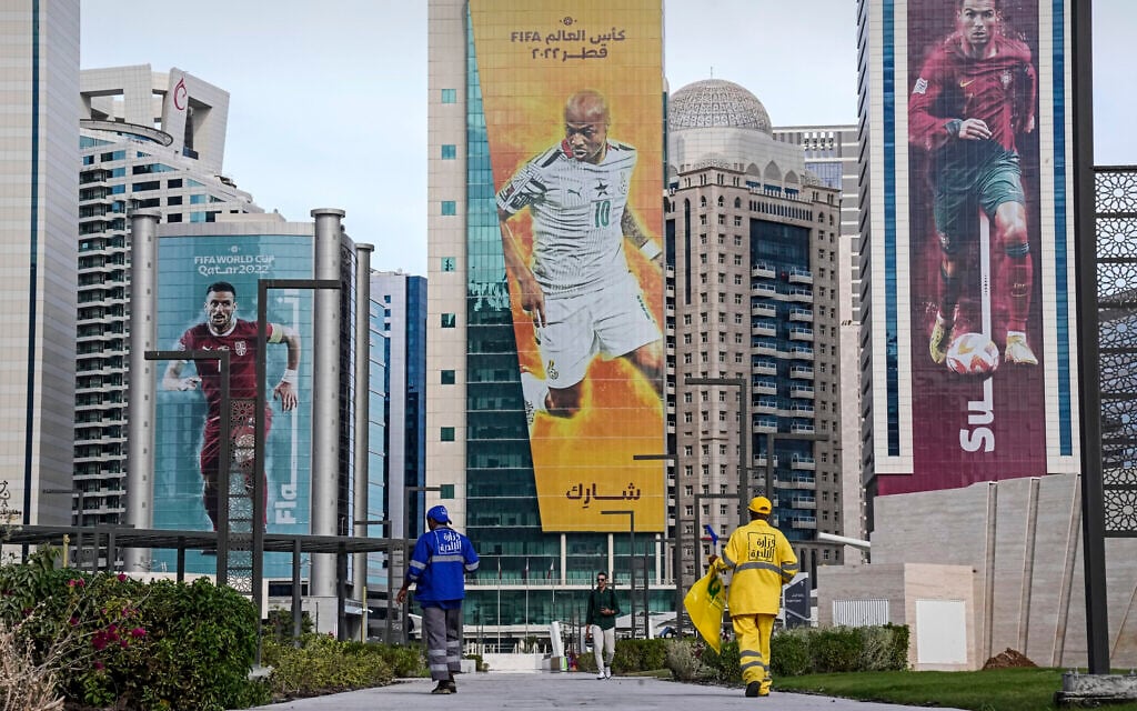 Two workers clean a street in front of skyscrapers with the giant pictures of soccer stars Cristiano Ronaldo of Portugal, Andre Ayew of Ghana and Dusan Tadic of Serbia, from right, in Doha, Qatar, Tuesday, November 29, 2022. (AP/Martin Meissner) Two workers clean a street in front of skyscrapers with the giant pictures of soccer stars Cristiano Ronaldo of Portugal, Andre Ayew of Ghana and Dusan Tadic of Serbia, from right, in Doha, Qatar, Tuesday, November 29, 2022. (AP/Martin Meissner)