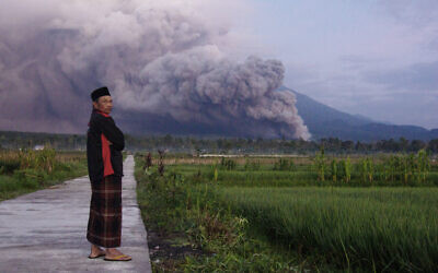A man looks on as Mount Semeru releases volcanic materials during an eruption on December 4, 2022 in Lumajang, East java, Indonesia (AP Photo)