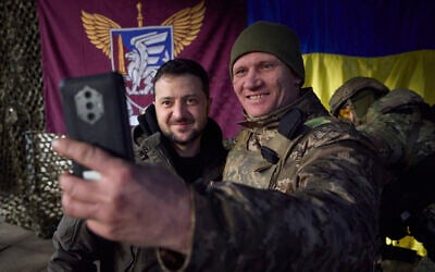 A Ukrainian soldier takes a selfie with President Volodymyr Zelensky, left, during his visit to Sloviansk, Donbas region, Ukraine, December 6, 2022. (Ukrainian Presidential Press Office via AP)