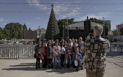 Tourists take pictures with the Christmas tree in Manger Square, adjacent to the Church of the Nativity in Bethlehem, Dec. 3, 2022. (AP Photo/ Mahmoud Illean)