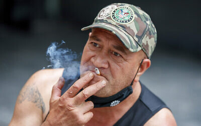 File: A man sits while smoking in Auckland, New Zealand, Thursday, Dec. 9, 2021 (AP Photo/David Rowland, File)