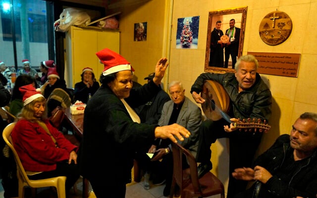 Amira Mansour (C) dances as Samir Damouni plays the Oud during a community Christmas dinner for elderly residents at the only majority-Christian Palestinian refugee camp, in Dbayeh, north of Beirut, Lebanon, December 21, 2022. (AP/Bilal Hussein) Amira Mansour (C) dances as Samir Damouni plays the Oud during a community Christmas dinner for elderly residents at the only majority-Christian Palestinian refugee camp, in Dbayeh, north of Beirut, Lebanon, December 21, 2022. (AP/Bilal Hussein)