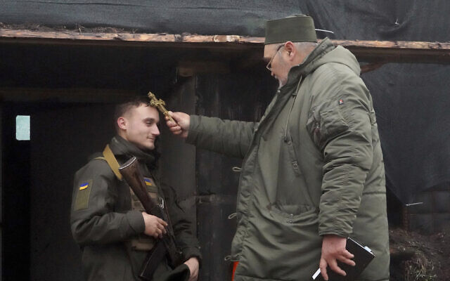 A chaplain blesses a soldier to mark Christmas at Ukraine's National Guard position close to the Russian border near Kharkiv, Ukraine, Dec. 24, 2022. (AP Photo/Andrii Marienko)