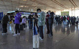 Masked travelers use their smartphones to fill in their health declaration after checking in at the international flight check in counter at the Beijing Capital International Airport in Beijing, Dec. 29, 2022. (AP/Andy Wong)