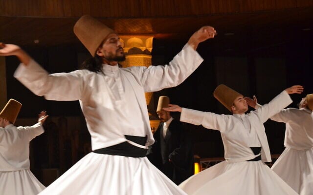 Turkish Mevlevi Dervish Osman Sariaj, left, seen during a Sama ceremony commemorating the 749th death anniversary of Islamic Sufi mystic Rumi, at the Irfa Culture Center in Konya, Turkey, December 17, 2022. (Tobias Siegal/Times of Israel)