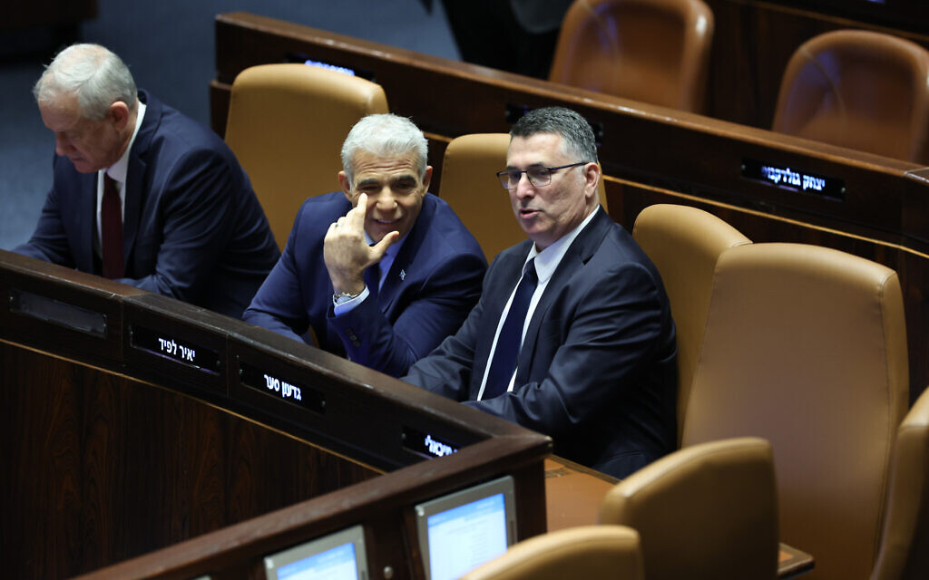 Outgoing justice minister Gideon Sa'ar, right, and outgoing prime minister Yair Lapid at the swearing-in ceremony of the new Netanyahu government at the Knesset, December 29, 2022. (Yonatan Sindel/FLASH90)