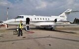 An airport employee stands in front of a Hawker 800 private plane that landed safely at Ben Gurion Airport after fears that it was missing a tire, December 23, 2022. (IAA spokesperson)