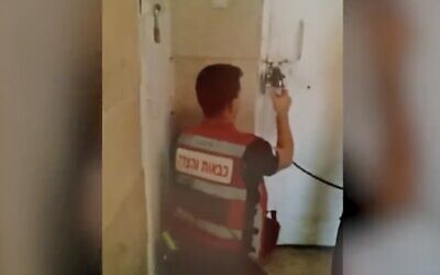 This screenshot of video released by police shows a first responder breaking the lock on a shelter in the central city of Lod, where two Palestinian teenagers illegally in Israel were held against their will. (Screen capture from Twitter, used in accordance with Clause 27a of the Copyright Law)