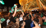 Illustrative: Maccabi Haifa fans watch the watch a match between Hapoel Be'er Sheva and Maccabi Haifa in Haifa, on May 30, 2021. (Yossi Aloni/Flash90/File)