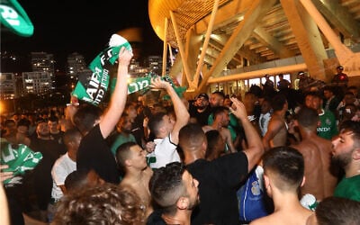 Illustrative: Maccabi Haifa fans watch the watch a match between Hapoel Be'er Sheva and Maccabi Haifa in Haifa, on May 30, 2021. (Yossi Aloni/Flash90/File)