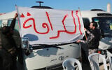 Jordanian bus drivers lift a banner bearing a slogan which reads "dignity" in Arabic as they continue a strike that started more than 10 days earlier to protest increasing fuel prices, on December 16, 2022 in the southern province of Maan. (Khalil Mazraawi/AFP)