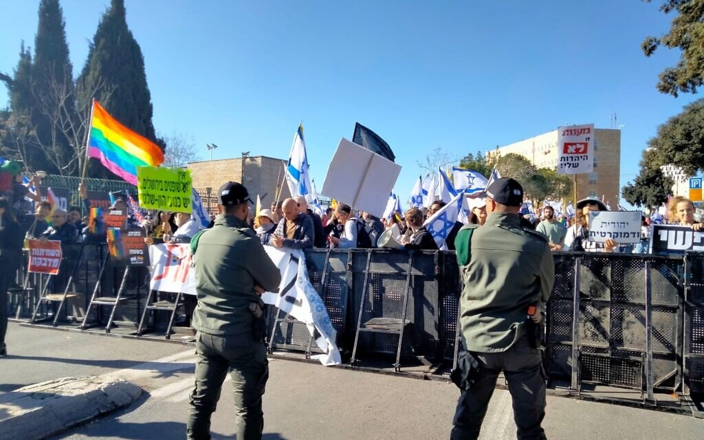 Protesters wave flags and hold banners against Benjamin Netanyahu's new government in front of the Knesset in Jerusalem, December 29, 2022. (Miri Pomerantz)
