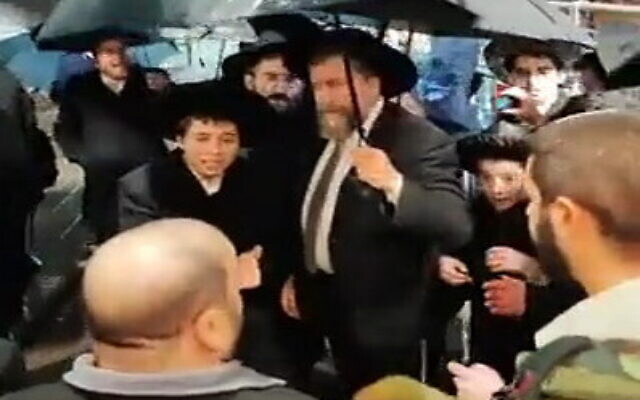 A group of ultra-Orthodox protesters attempt to enter a cultural hall in Jerusalem where ultra-Orthodox are holding a Hanukkah candle-lighting event, December 25, 2022. (Screenshot: Twitter) A group of ultra-Orthodox protesters attempt to enter a cultural hall in Jerusalem where ultra-Orthodox are holding a Hanukkah candle-lighting event, December 25, 2022. (Screenshot: Twitter)