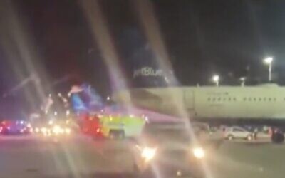 A JetBlue plane is evacuated at New York's John F. Kennedy International Airport after a laptop started emitting smoke, December 24, 2022 (Screen grab via CBS used in accordance with Clause 27a of the Copyright Law)