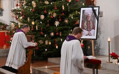 A photograph of late former Pope Emeritus Benedict XVI is seen during a Rosary prayer in the Catholic St Oswald church in his birth town Marktl am Inn, southern Germany, on January 1, 2023, the day after his death (KERSTIN JOENSSON / AFP)