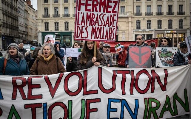A woman holds a placard reading in French as 'close the mullahs' embassy' during a rally in Lyon on January 8, 2023 against the Iranian regime (JEAN-PHILIPPE KSIAZEK / AFP)