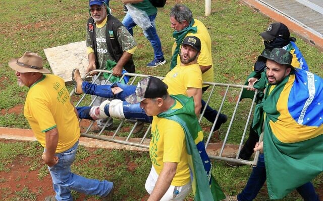 A supporter of Brazilian former President Jair Bolsonaro is evacuated by fellow supporters after being wounded during clashes with riot police outside Planalto Presidential Palace in Brasilia on January 8, 2023. (Sergio Lima / AFP) A supporter of Brazilian former President Jair Bolsonaro is evacuated by fellow supporters after being wounded during clashes with riot police outside Planalto Presidential Palace in Brasilia on January 8, 2023. (Sergio Lima / AFP)