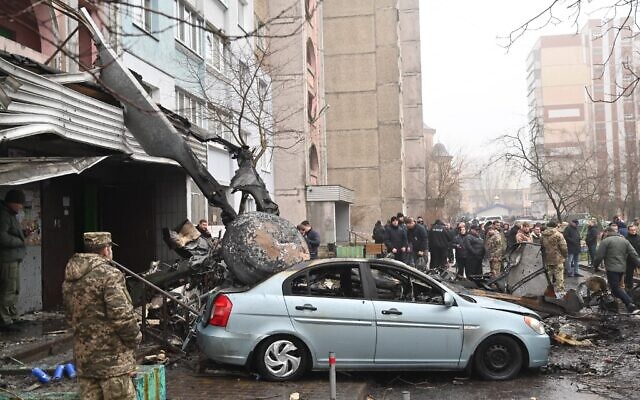 Military and onlookers stand at the site where a helicopter crashed near a kindergarten outside the capital Kyiv on January 18, 2023, amid the Russian invasion of Ukraine. (Sergei Supinsky / AFP)