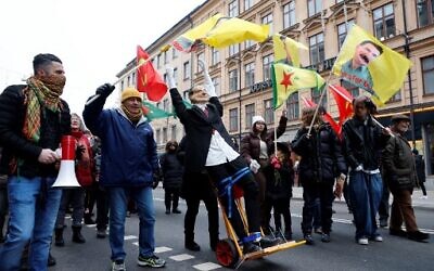 Protesters wave flags showing the face of Abdullah Ocalan, the leader of the Kurdistan Worker's Party (PKK) and march with an effigy of Turkish President Recep Tayyip Erdogan, during a demonstration organized by The Kurdish Democratic Society Center against Erdogan and Sweden's NATO bid, in Stockholm on January 21, 2023. (Christine OLSSON/TT News Agency/AFP)