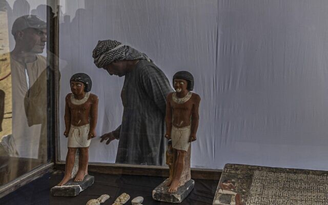 Workers stand behind a collection of pharaoh statues during a press conference at the Saqqara archaeological site, south of Cairo on January 26, 2023. (Khaled DESOUKI / AFP)