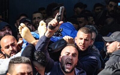 A man fires his gun into the air as Palestinians carry the body of one of the 9 reported victims killed during an Israeli raid on the West Bank's Jenin refugee camp, as they begin his funeral procession in the city of the same name on January 26, 2023. (Jaafar Ashtiyeh/AFP) A man fires his gun into the air as Palestinians carry the body of one of the 9 reported victims killed during an Israeli raid on the West Bank's Jenin refugee camp, as they begin his funeral procession in the city of the same name on January 26, 2023. (Jaafar Ashtiyeh/AFP)