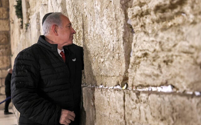 Prime Minister Benjamin Netanyahu places a prayer note between the cracks as he visits the Western Wall in the Old City of Jerusalem, January 1, 2023. (Gil Cohen-Magen/Pool via AP) Prime Minister Benjamin Netanyahu places a prayer note between the cracks as he visits the Western Wall in the Old City of Jerusalem, January 1, 2023. (Gil Cohen-Magen/Pool via AP)