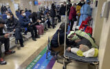 A woman looks after her elderly relative lying on a stretcher as patients receive intravenous drips in the emergency ward of a hospital in Beijing, Thursday, Jan. 5, 2023.  (AP Photo/Andy Wong)