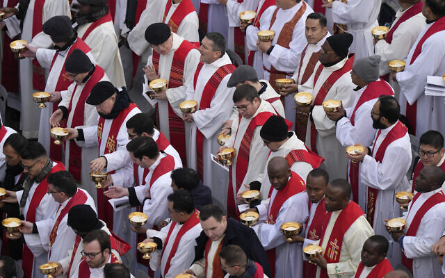Priests prepare for the holy communion during the funeral mass for late Pope Emeritus Benedict XVI in St. Peter's Square at the Vatican, Thursday, Jan. 5, 2023. Benedict died at 95 on Dec. 31 in the monastery on the Vatican grounds where he had spent nearly all of his decade in retirement. (AP Photo/Ben Curtis)