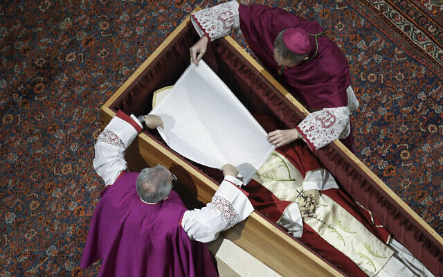 In this image released on Thursday, Jan. 5, 2023, by the Vatican Media news service, Bishops Georg Gaenswein, right, and Diego Ravelli cover the face of Pope Emeritus Benedict XVI with a white silk veil as he rests in a cypress coffin in St. Peter's Basilica, Wednesday, Jan. 4, 2023, the night before his funeral mass presided over by Pope Francis at the Vatican. Benedict died at 95 on Dec. 31 in the monastery on the Vatican grounds where he had spent nearly all of his decade in retirement. He was 95. (Vatican Media via AP)