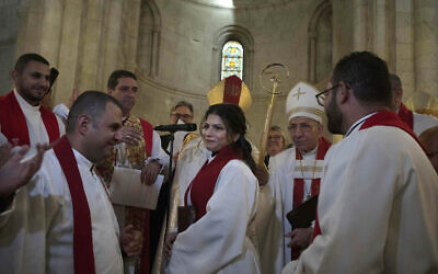 Sally Ibrahim Azar, center, a Palestinian Christian and Council member of the Lutheran World Federation is applauded by clergy after she was ordained as the first female pastor in the Holy Land, in the Old City of Jerusalem, January 22, 2023. (AP Photo/Maya Alleruzzo)