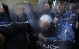 Anti-government protesters scuffle with riot police outside the Ministry of Justice, in Beirut, Lebanon on January 26, 2023. (AP Photo/Hassan Ammar)